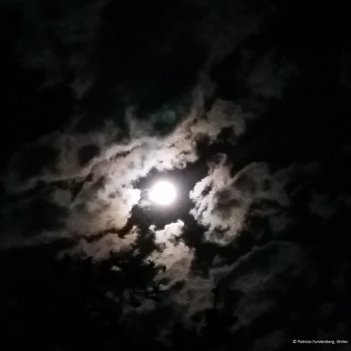full moon behind parting clouds