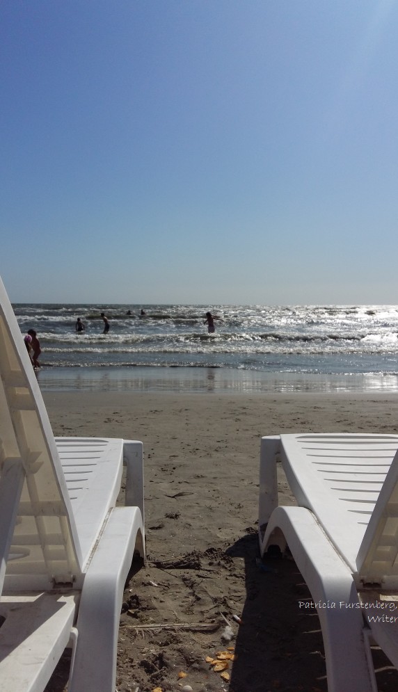 white beach chairs, gray sand, blue sea 10am light
